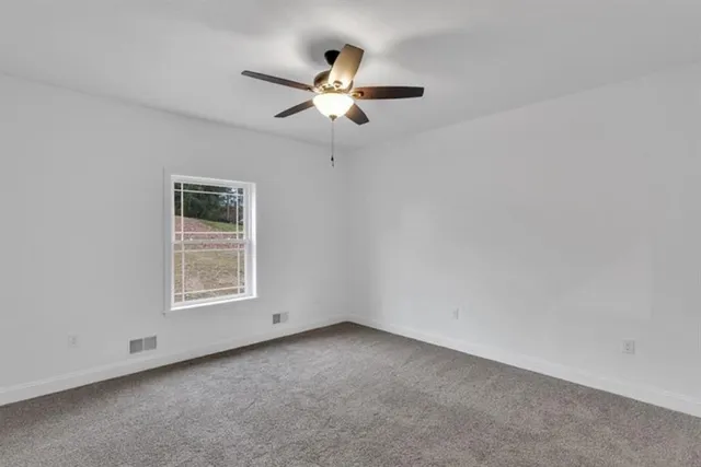 an empty room with a window and a fan