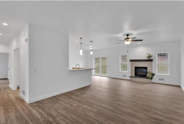 a view of an empty room with wooden floor and fireplace