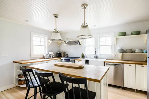 a kitchen with a dining table chairs and white cabinets
