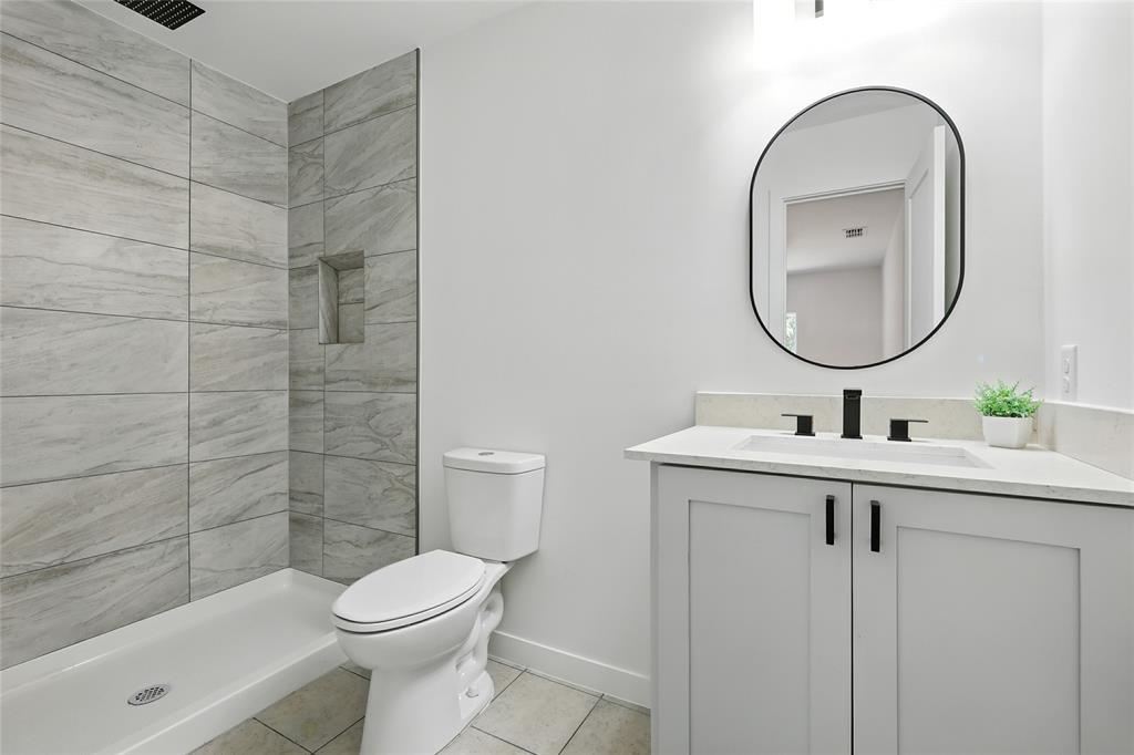 3122 Seevers Avenue Dallas, TX 75216 - Photo 10 of 16 a bathroom with a toilet a sink a mirror and shower