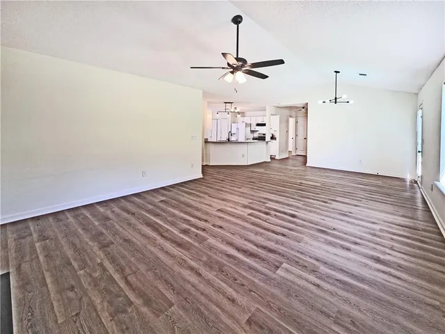 a view of a room with wooden floor ceiling fan and window