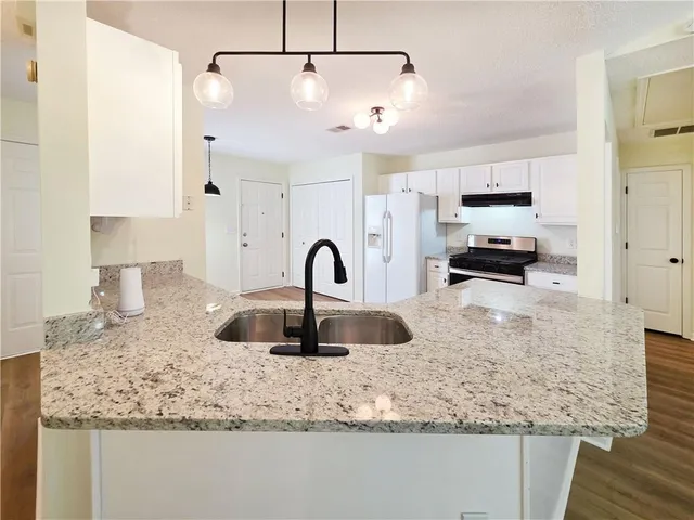 a kitchen with granite countertop a sink a counter top space and cabinets