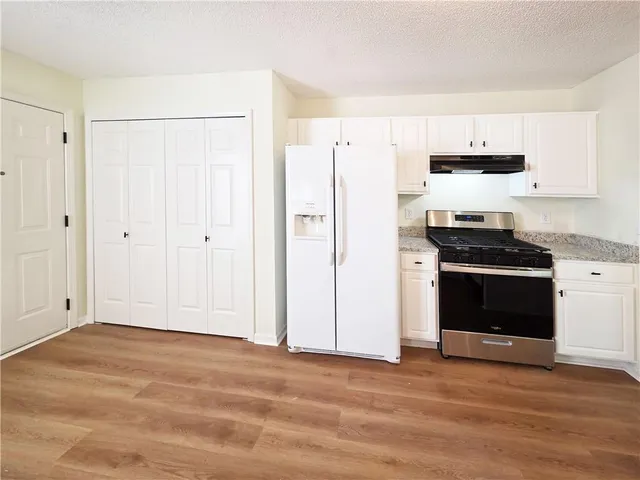 a kitchen with granite countertop white cabinets and stainless steel appliances