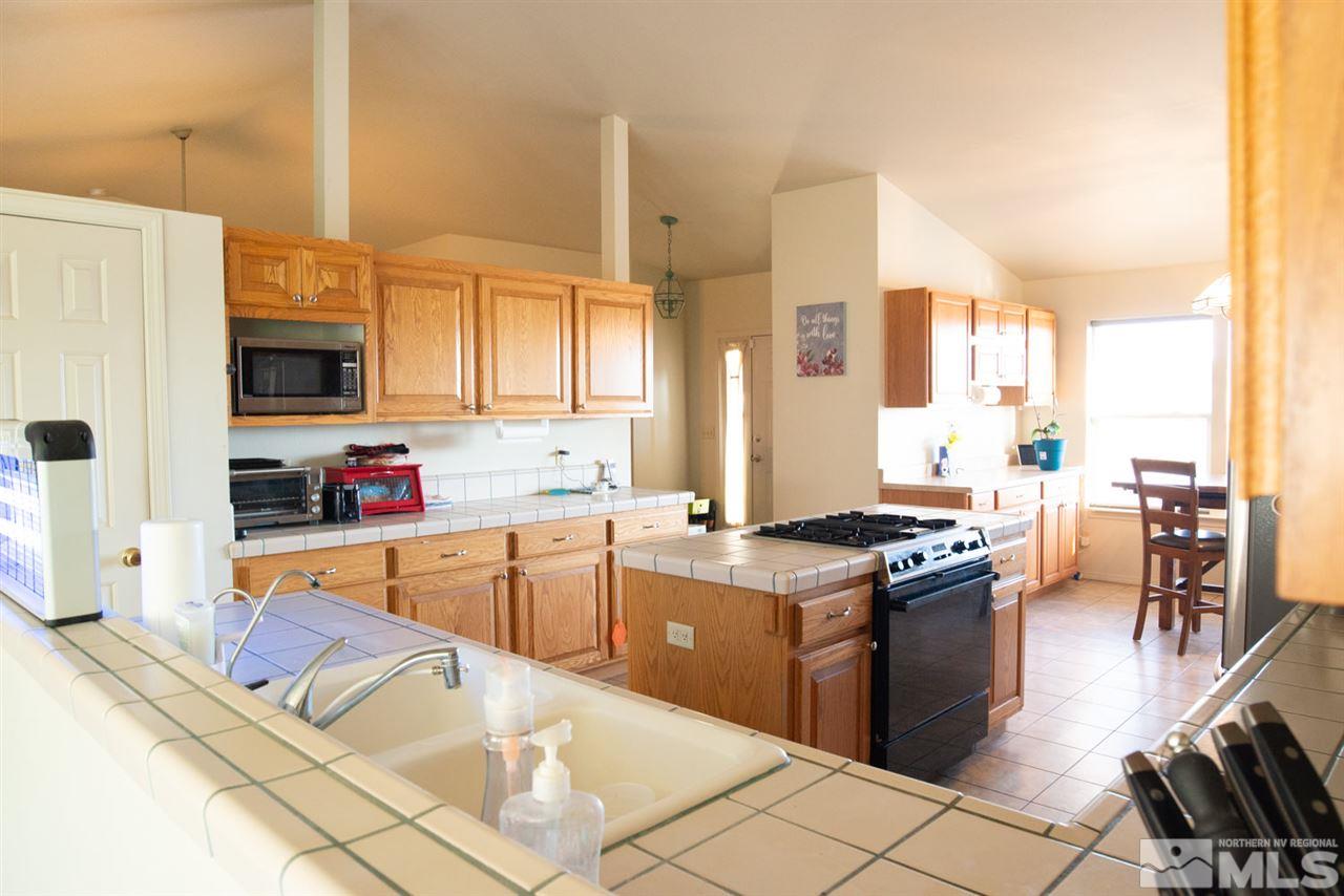 4080 Rancheria Road Fallon, NV 89406 - Photo 12 of 25 a kitchen with stainless steel appliances granite countertop a stove top oven a sink a dining table and chairs with the view of living room