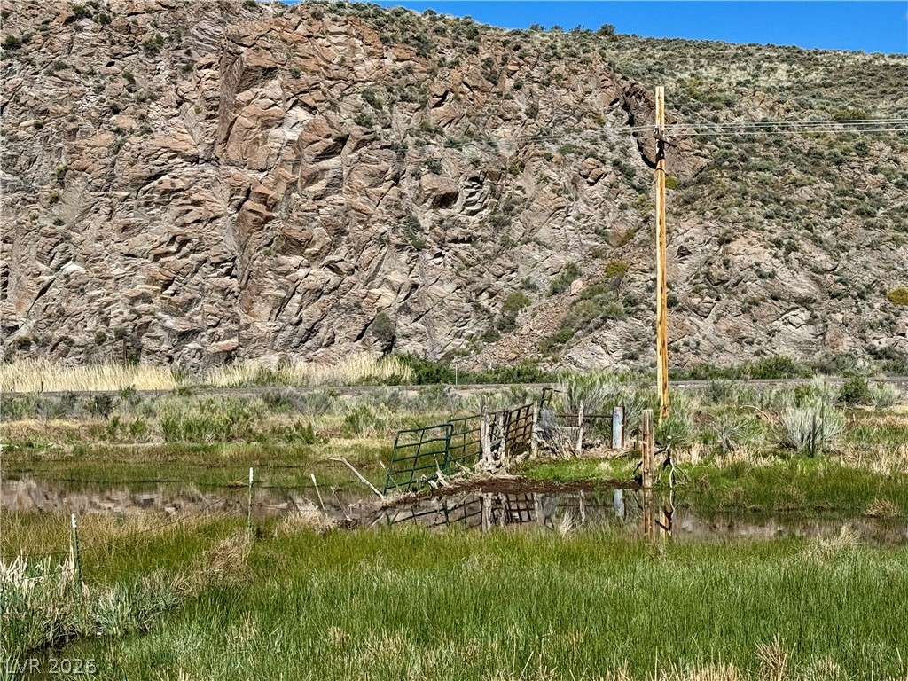 9393 North 93rd Highway Caliente, NV 89008 - Photo 40 of 41 Scenic views of rugged mountain terrain, a tranquil pond, and vibrant green grasses.
