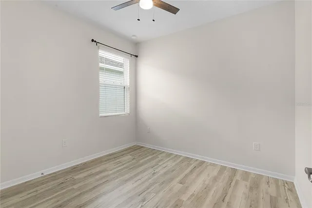 a view of an empty room with wooden floor and closet