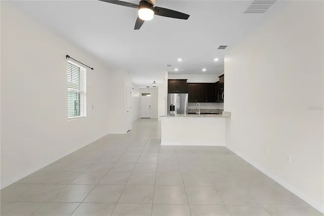 an empty room with wooden floor ceiling fan and windows