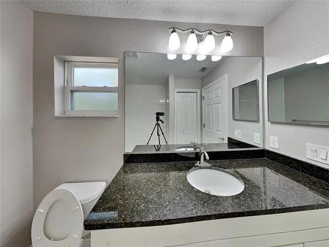 a bathroom with a granite countertop sink and a mirror