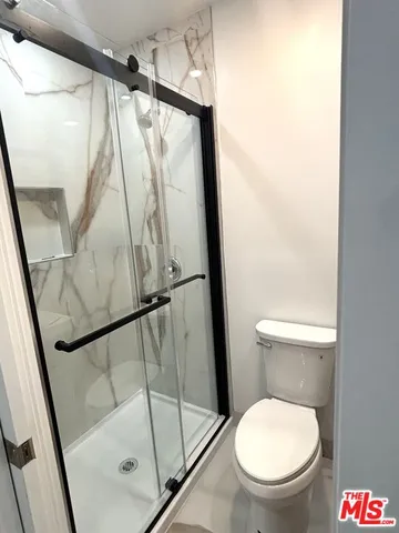 a white toilet sitting next to a shower