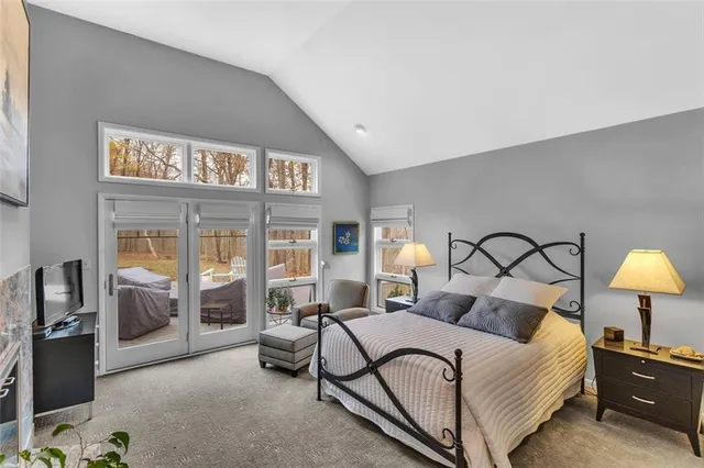 a bedroom with a bed chair and a lamp on dresser next to a window