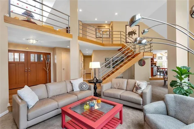 a living room with furniture kitchen view and a chandelier