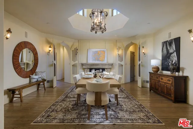a living room with dining table a mirror and a chandelier