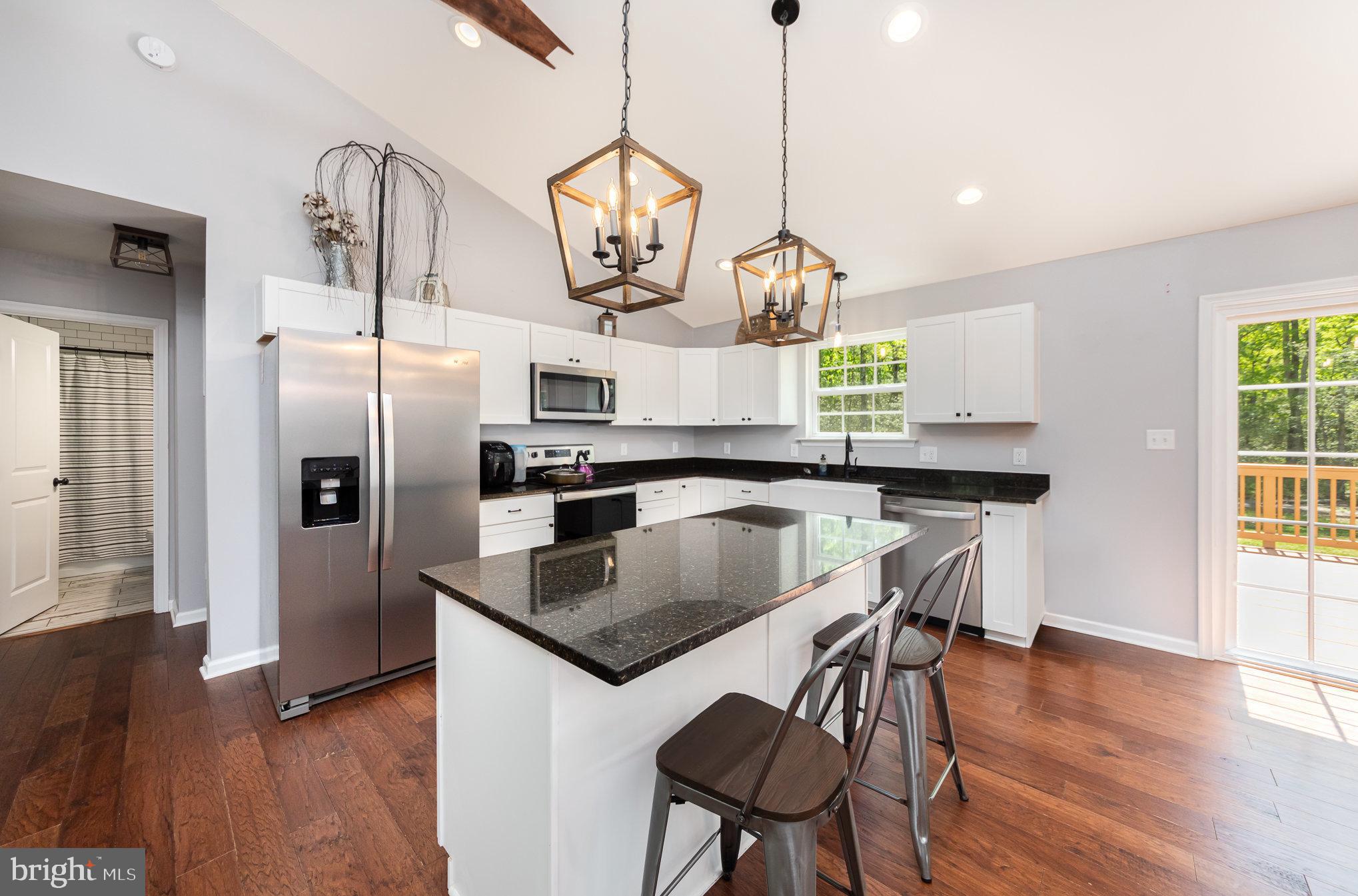 7464 Cedar Fork Road Ruther Glen, VA 22546 - Photo 6 of 24 a kitchen with stainless steel appliances granite countertop a sink a refrigerator and wooden floor