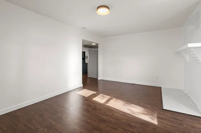 a view of a big room with wooden floor and windows