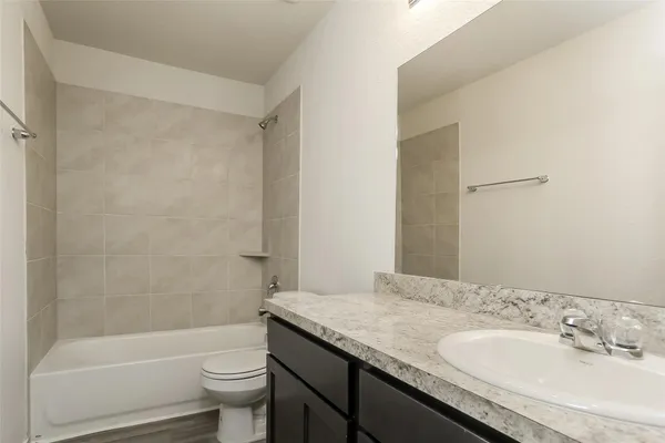 a bathroom with a granite countertop sink a toilet and shower