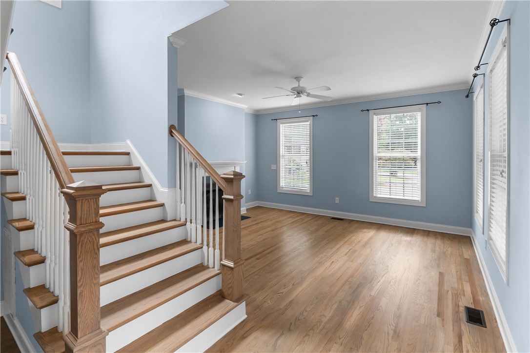 206 Village Way Pendleton, SC 29670 - Photo 4 of 46 A grand wooden staircase with white risers leads to an upper level, complementing the bright living space featuring gleaming hardwood floors.