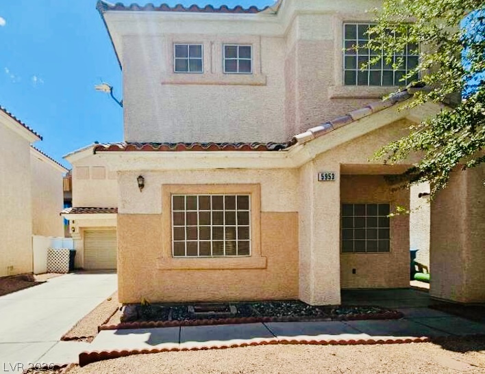 5953 Crumbling Ridge Street Henderson, NV 89011 - Photo 2 of 42 A welcoming facade with a covered entry and tile roof accents a desert-friendly landscape.