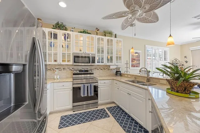 a kitchen with stainless steel appliances a sink a stove a chimney a refrigerator and cabinets