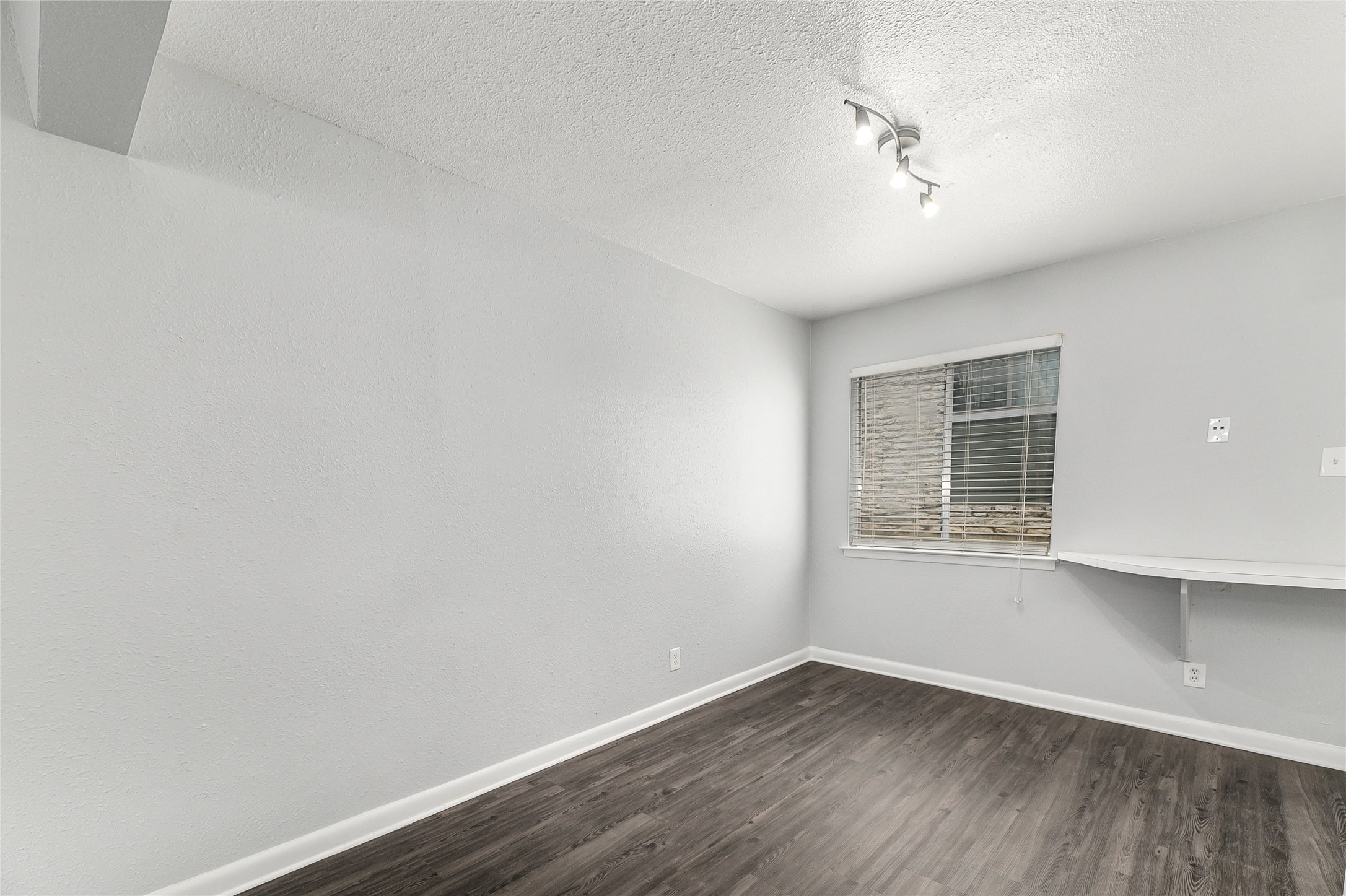 2408 Longview Street, Unit 113 Austin, TX 78705 - Photo 6 of 23 Spare room featuring dark wood-style flooring, a textured ceiling, and track lighting