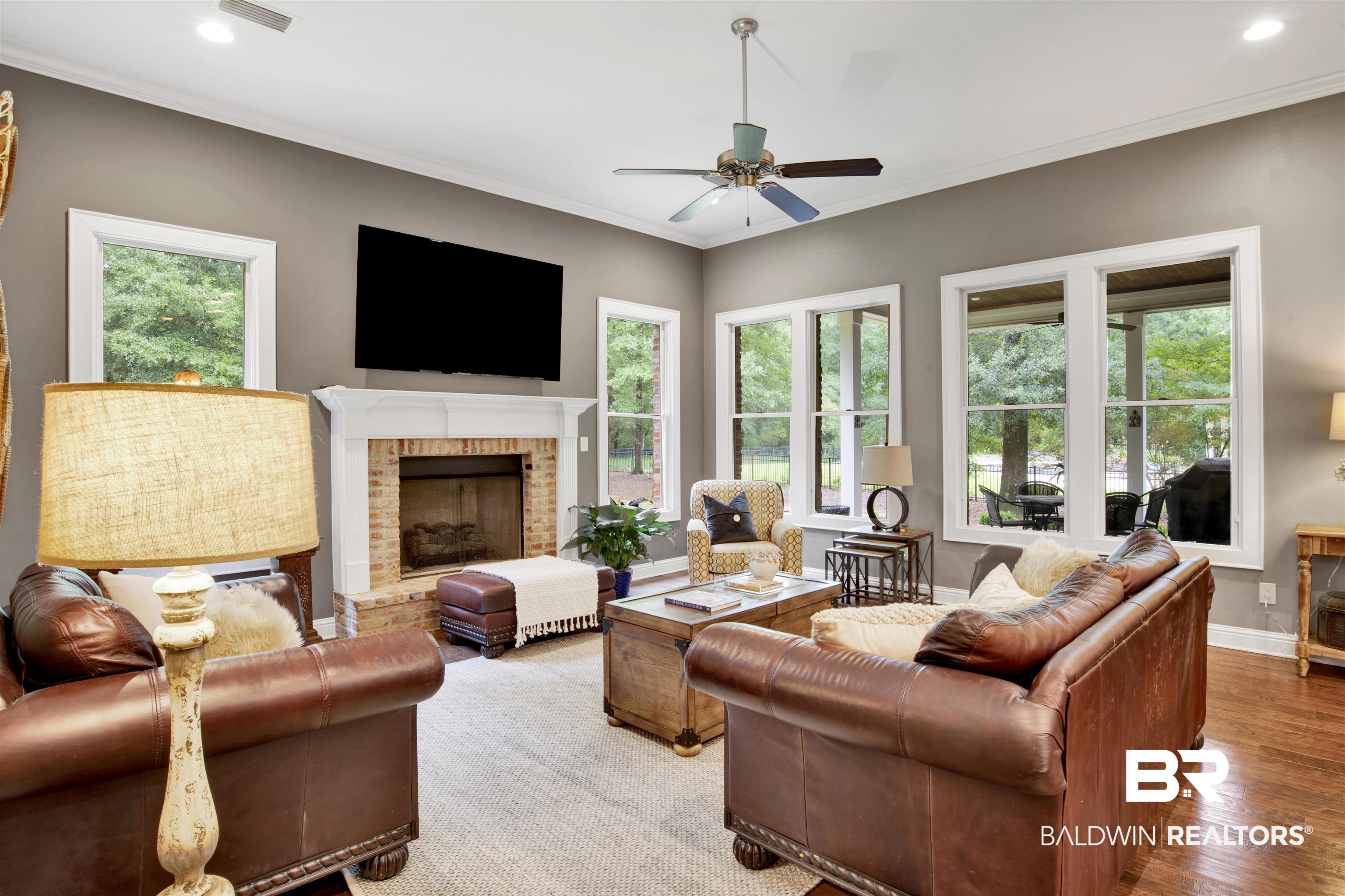 11244 Redfern Road Daphne, AL 36526 - Photo 13 of 50 Living room with crown molding, ceiling fan, light wood-type flooring, and a brick fireplace