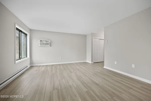 a view of an empty room with a window and wooden floor