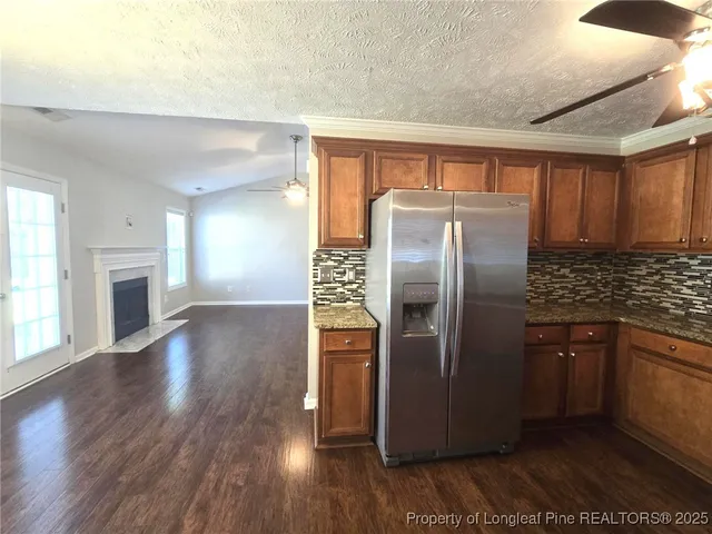 a kitchen with granite countertop a refrigerator and a stove top oven