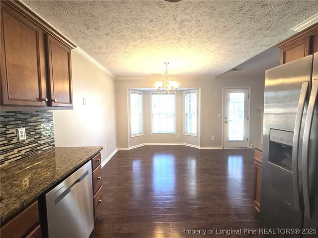 a kitchen with stainless steel appliances granite countertop a refrigerator a sink dishwasher a stove and white countertops with wooden floor