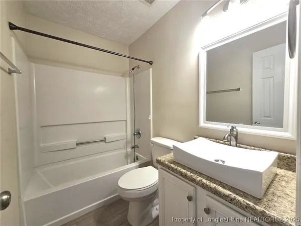 a bathroom with a granite countertop sink toilet mirror and shower