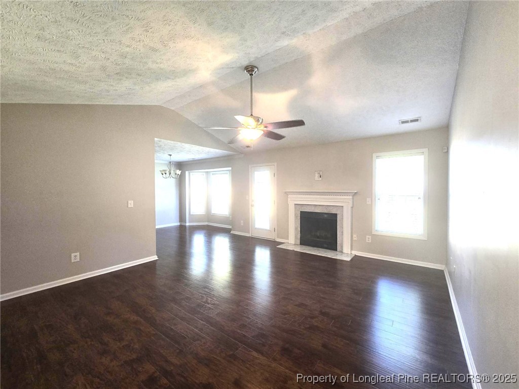 1540 Clan Campbell Drive Raeford, NC 28376 - Photo 6 of 35 an empty room with wooden floor chandelier fan and windows