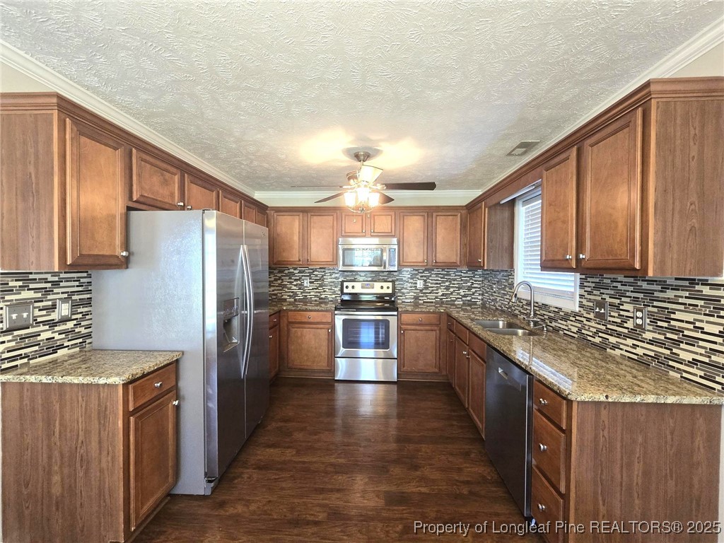 1540 Clan Campbell Drive Raeford, NC 28376 - Photo 10 of 35 a large kitchen with stainless steel appliances granite countertop a stove a sink dishwasher a refrigerator and wooden cabinets