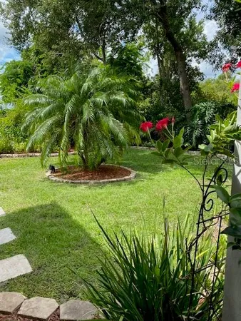 a view of a white house with a big yard and potted plants