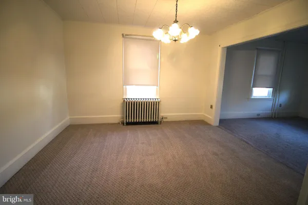 an empty room with chandelier fan and windows