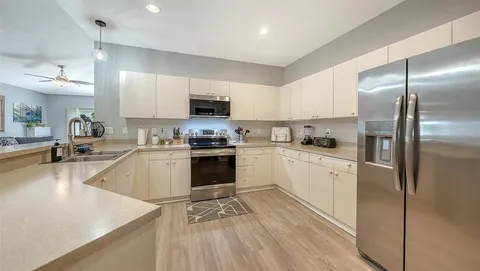 a kitchen with kitchen island a counter top space a sink stainless steel appliances and cabinets