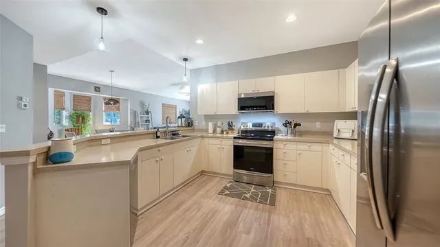 a kitchen with kitchen island a counter top space a sink stainless steel appliances and cabinets