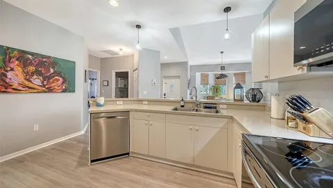a large kitchen with a large counter top space a sink stainless steel appliances and cabinets
