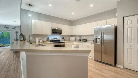 a kitchen with stainless steel appliances granite countertop a refrigerator a sink a stove a microwave and island