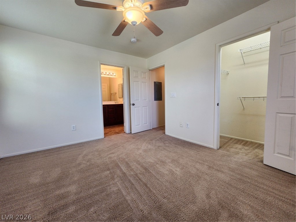 9132 Ripple Ridge Avenue, Unit 102 Las Vegas, NV 89149 - Photo 22 of 42 Unfurnished bedroom featuring light colored carpet, a ceiling fan, a spacious closet, and connected bathroom