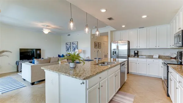 a kitchen with kitchen island granite countertop a sink and refrigerator