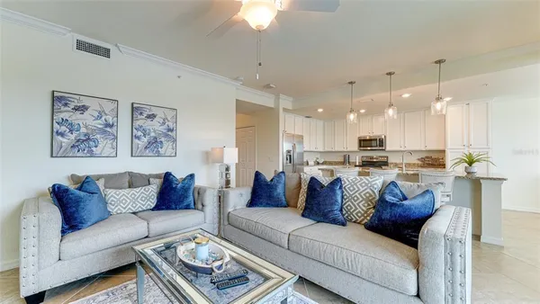 a living room with furniture kitchen view and a chandelier