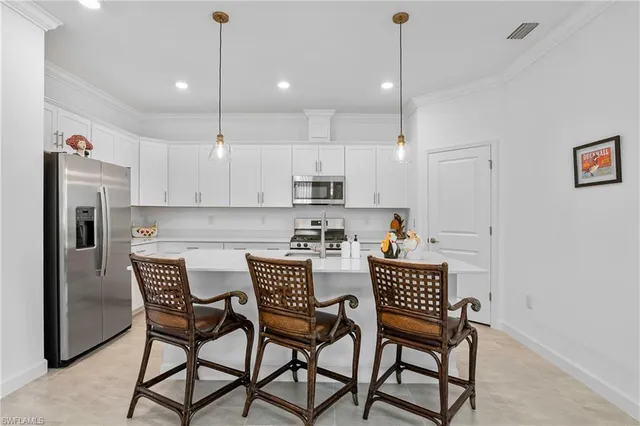 a kitchen with stainless steel appliances granite countertop a dining table chairs and a refrigerator