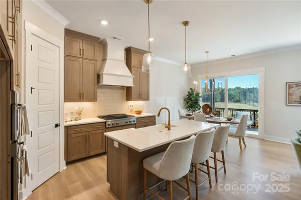 a kitchen with stainless steel appliances granite countertop a stove a sink a refrigerator a dining table and chairs with wooden floor