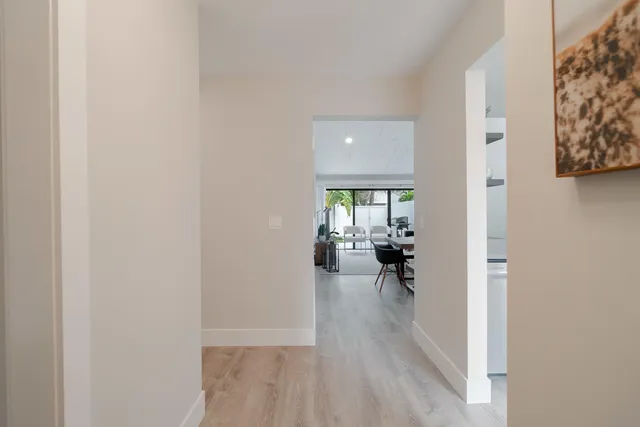 a view of a hallway with wooden floor and a livingroom with furniture