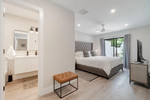 a bedroom with a bed a couch and a flat tv screen on the dresser