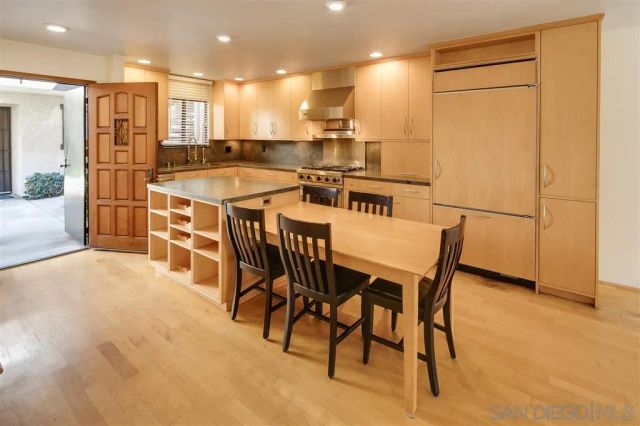 a kitchen with stainless steel appliances kitchen island granite countertop a table chairs and a refrigerator