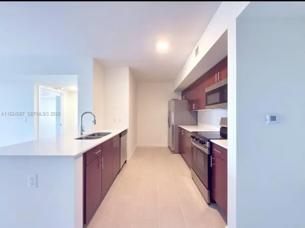 a large kitchen with stainless steel appliances a sink and cabinets