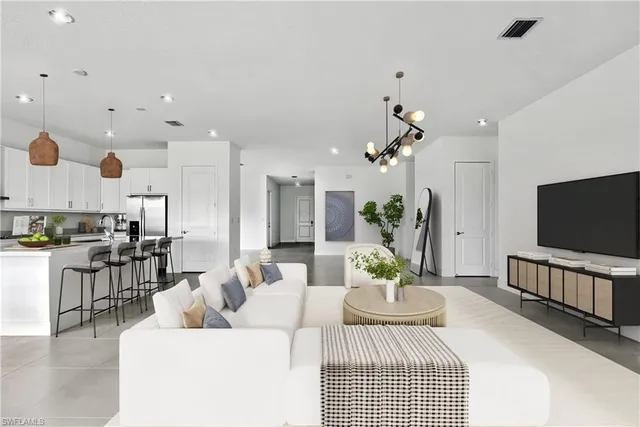 a living room with furniture a flat screen tv and kitchen view