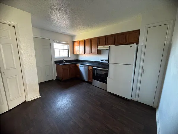 a kitchen with a refrigerator a stove top oven and wooden floor