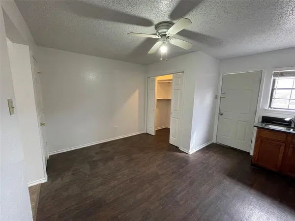 an empty room with wooden floor fan and windows