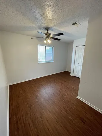 an empty room with wooden floor chandelier fan and windows