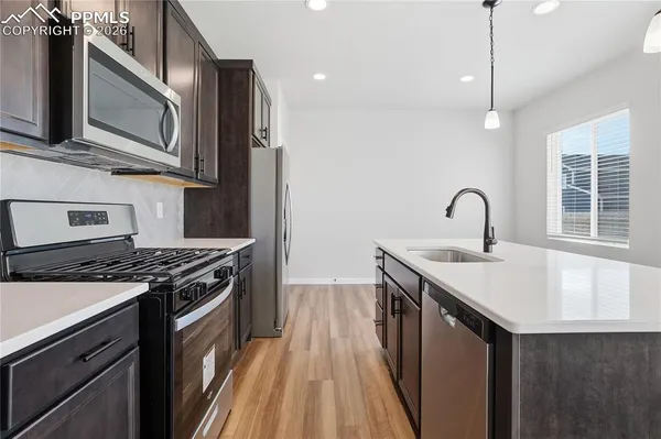 a kitchen with stainless steel appliances granite countertop a sink a stove top oven and refrigerator